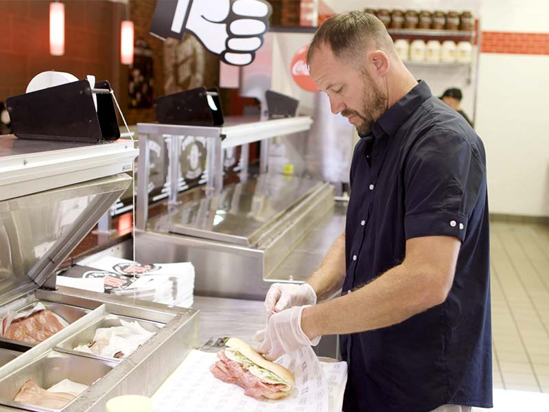 Tommy Stuckey works at his sub shop counter preparing an order for a customer.