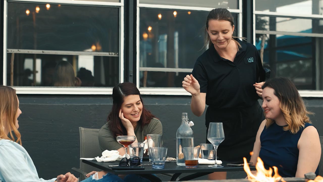 A server waits on a table of patrons at a restaurant.