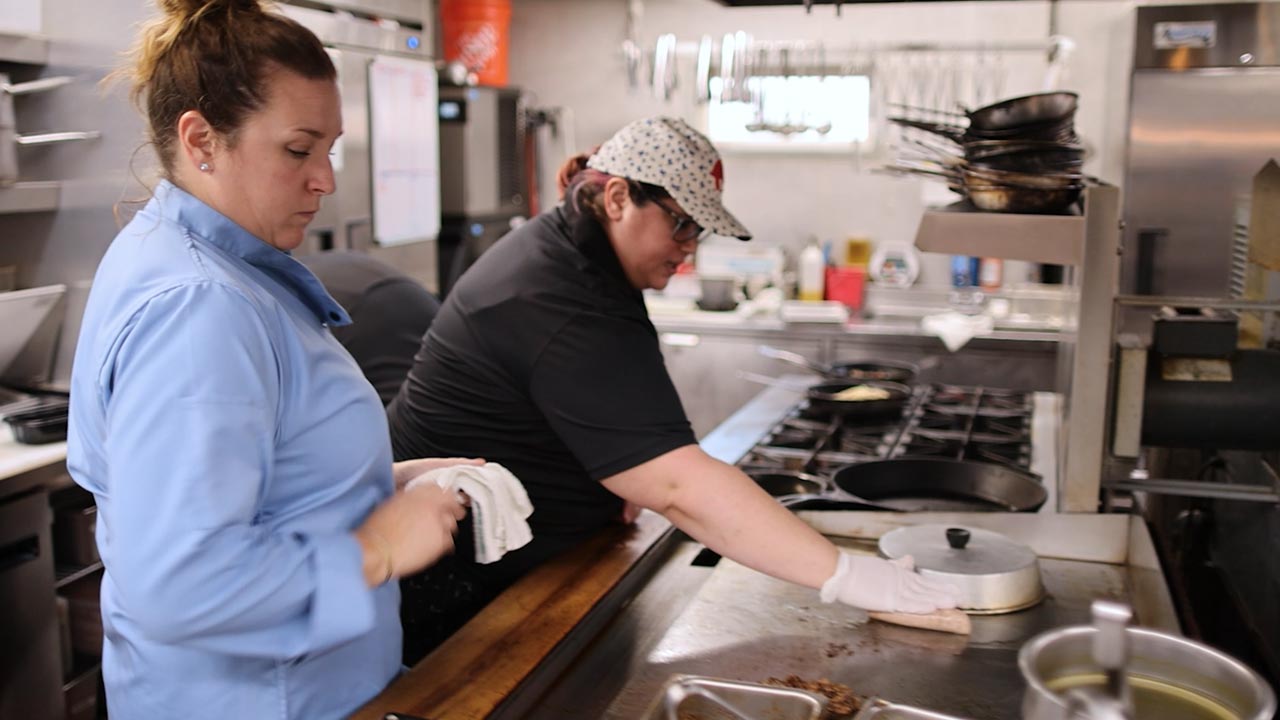 A restaurant owner works alongside her employees in the kitchen.