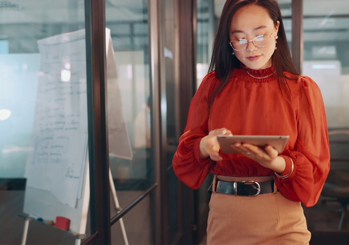 Women walking on office hallway while looking at a tablet 