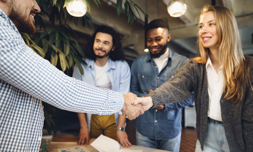 Small Business owner with her team welcoming a new employee with a handshake