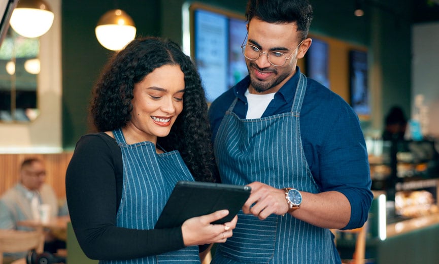 A small business owner training and developing their employee on a tablet