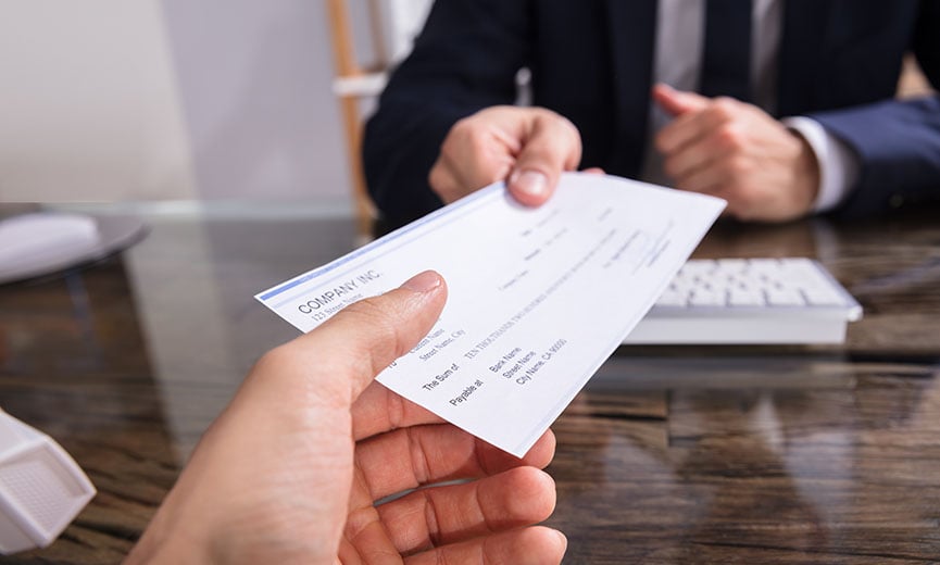 Un empleador entrega a un empleado un cheque de pago después de retener las cantidades correspondientes a las deducciones de nómina