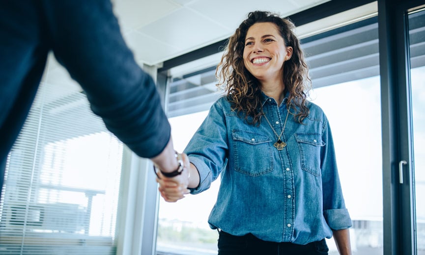 Reclutador que está estrechándole la mano a un candidato interno o externo en un entorno de oficina