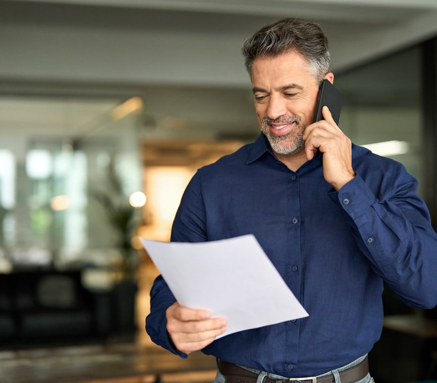 Middle age insurance agent on phone with client in an office setting