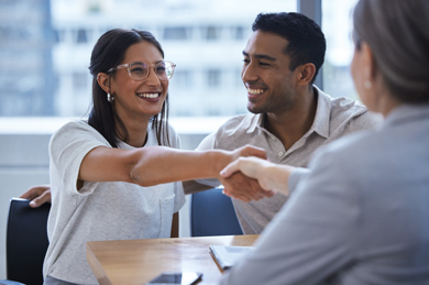 Two small business owners shaking hands with a insurance agent in a office building