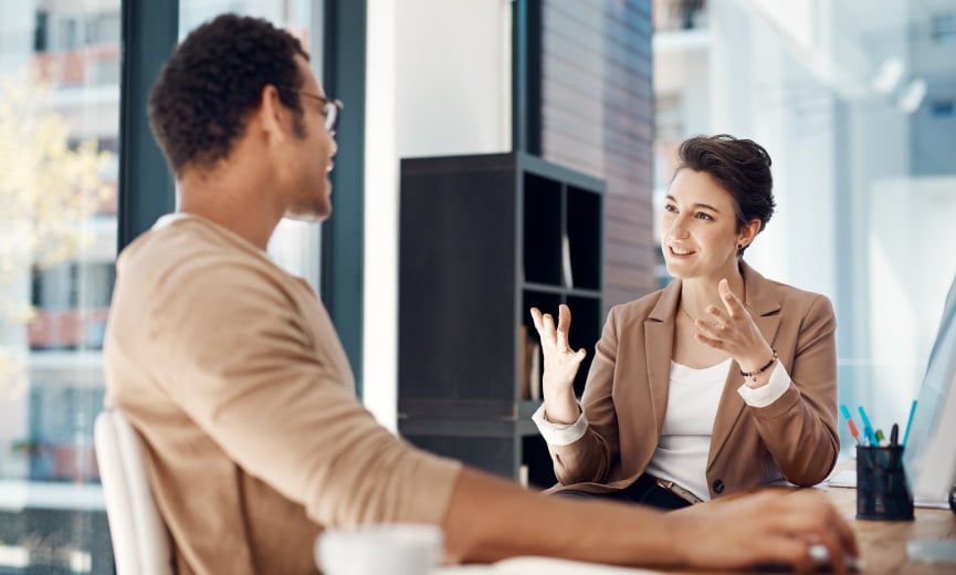 A manager coaching and helping another employee in an office setting