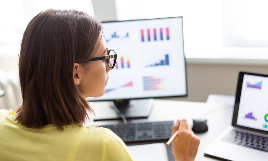 A human resources professional looking at metrics on a two screens