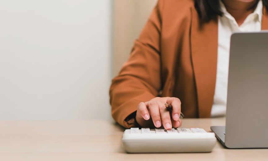 Business owner calculating payroll on a calculator