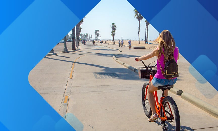 Young woman riding bicycle on california beach