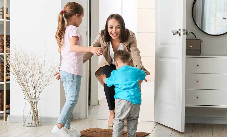 dos niños felices saludan a su madre en la puerta después de que ella termina su semana laboral de cuatro días
