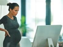 Mujer embarazada se toma un descanso de su computadora en la oficina.