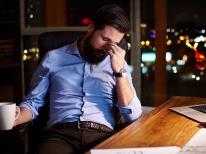 White-collar worker looking tired at his desk, representing working overtime 