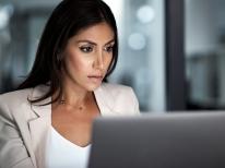 A business woman looks for data on computer for employees who might have taken premium tax credit.