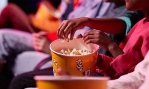family eat popcorn while attending a movie in a theater