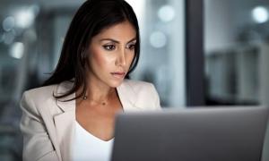 A business woman looks for data on computer for employees who might have taken premium tax credit.