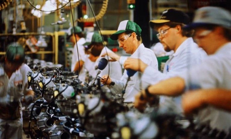 Workers on an assembly line are building automobiles.