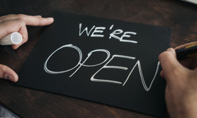 Un propietario de negocio crea un letrero que dice "abierto" para la ventana.