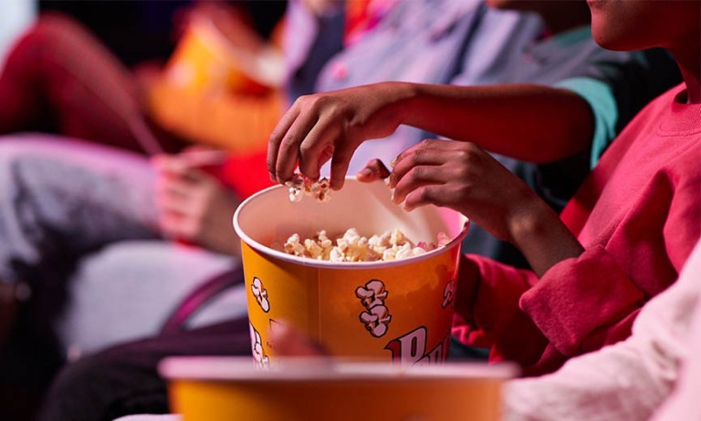 miembros de una familia comen palomitas mientras ven una película en un sala de cine