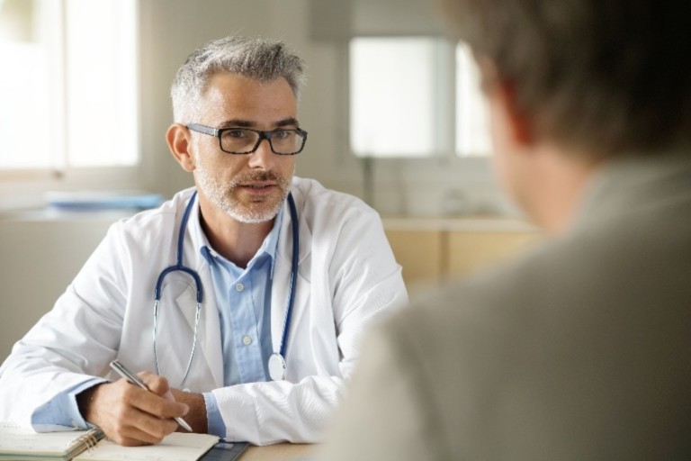 Un médico habla con un paciente en un consultorio sobre seguros médicos
