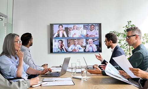 Grupo de empleados sentados a una mesa que miran una pantalla