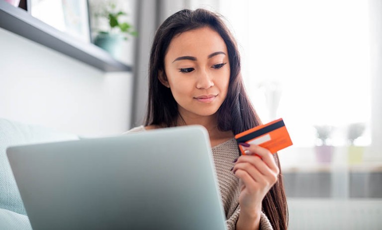 una mujer que usa una tarjeta de crédito para hacer una transacción en línea con impuestos sobre las ventas