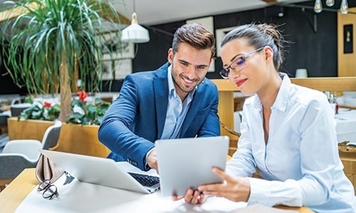 Hombre y mujer que trabajan en la mesa con una computadora portátil y una tableta