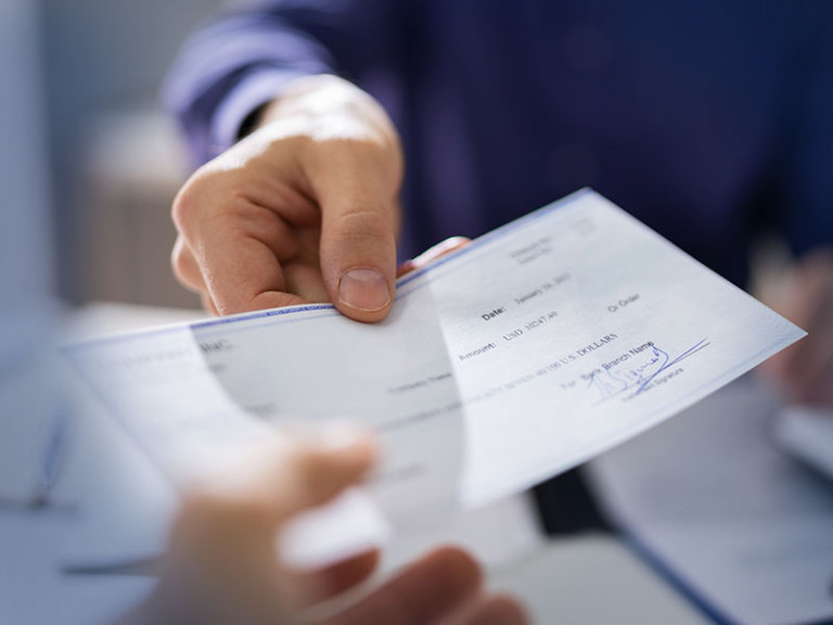 A person handing a paycheck to an employee