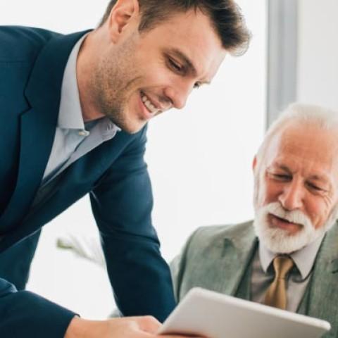 Two men representing different generations in the workforce working on a project together using technology