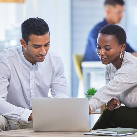 two people talking and working on a laptop
