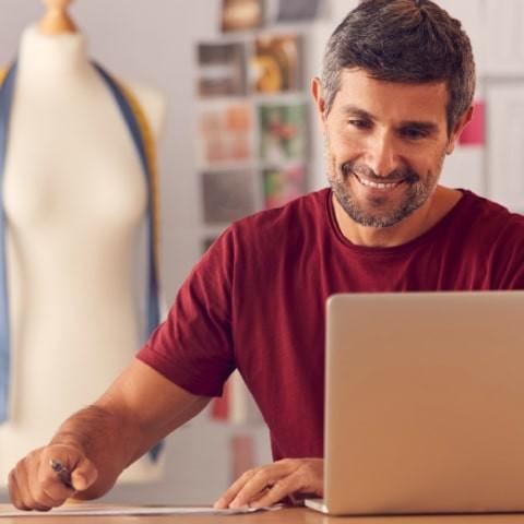 man working on laptop in a clothing design studio