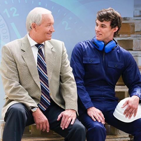 An executive talking to a worker in front of a construction