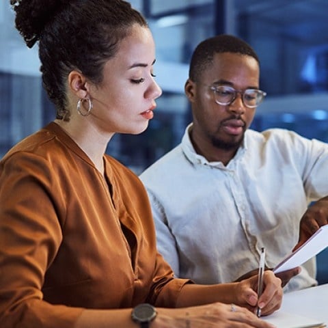 two payroll professionals working on a document together