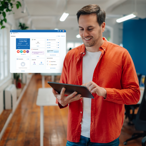 A person stands in a modern office holding a tablet, with a digital dashboard interface floating beside them and desks, chairs, and plants visible in the background