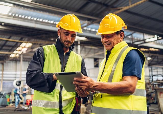 two construction workers looking at a tablet