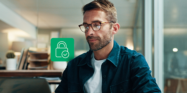Person working on a laptop in a modern office setting, accompanied by a padlock icon that represents secure data access, privacy, and compliance.
