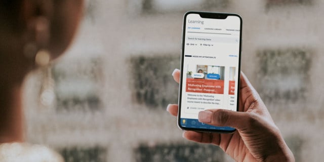 An employee using her learning management system on a mobile device