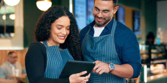 A small business owner training and developing their employee on a tablet
