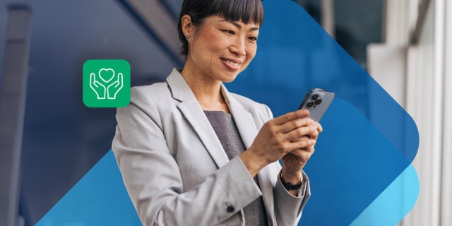 A person in professional attire uses a smartphone with a wellness‑themed icon displayed beside them