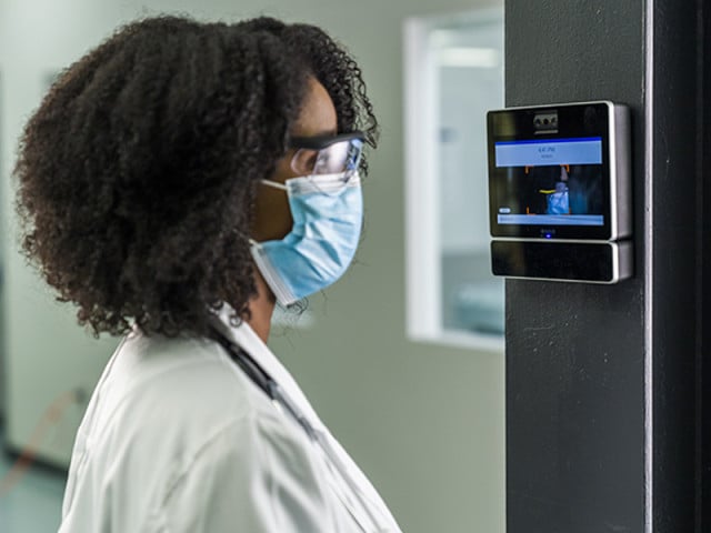 An employee clocking in with a touchless timeclock