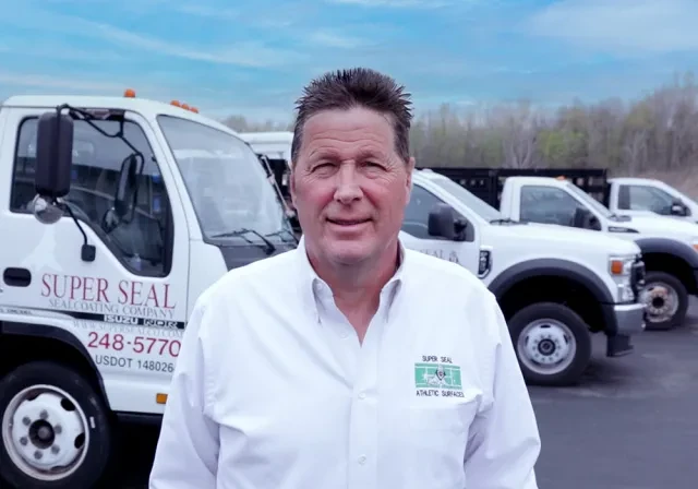 Greg Duffy posa fuera de la flota de camiones para su negocio Super Seal Sealcoating.