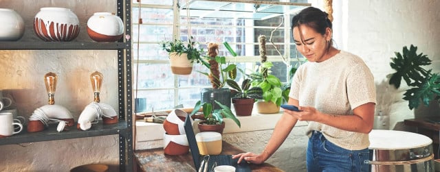 Propietaria de una pequeña empresa que trabaja con su teléfono y computadora