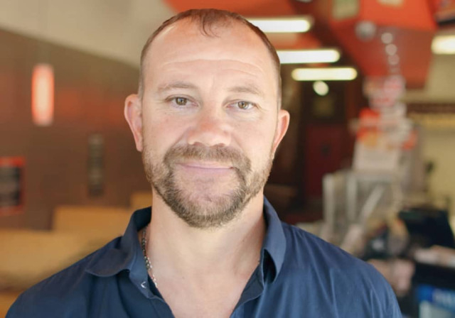 balding store owner with beard smiles