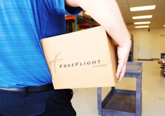 employee carries box labeled "Free Flight" under arm