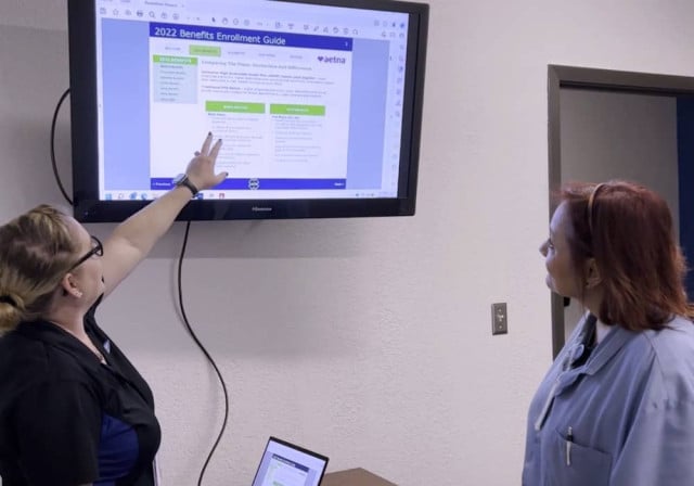 woman points to computer screen while second woman looks on
