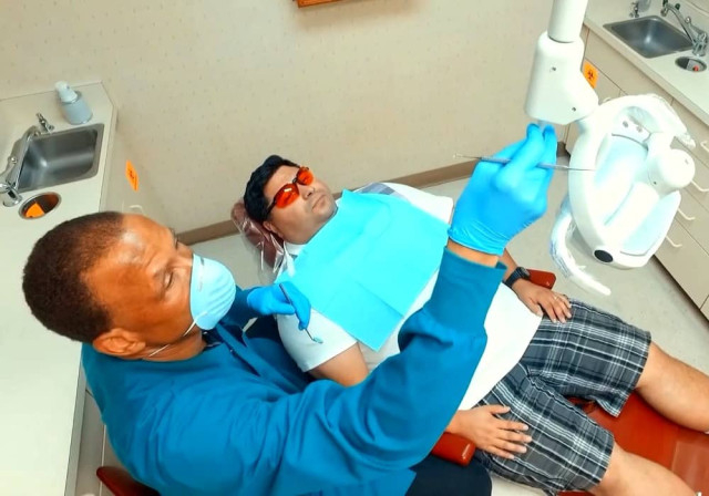 higienista dental regula la iluminación sobre el joven paciente adulto sentado en la silla
