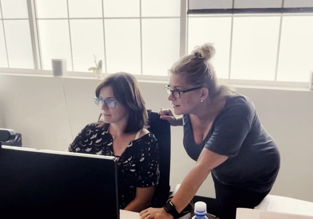dos mujeres miran la computadora en la oficina de Verve Partnership Studio de Baltimore, MD