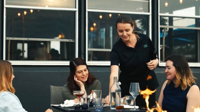 waittress serves platter to outdoor guests