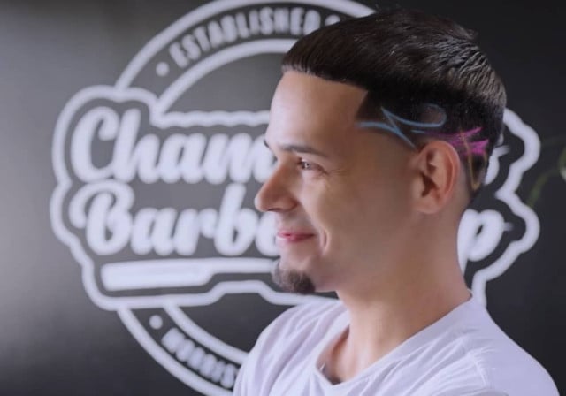 corte de pelo de estilo moderno en un cliente masculino frente al logotipo de champion's barbershop
