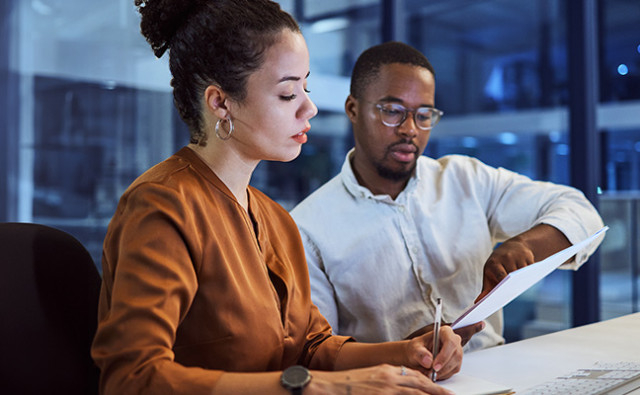 two payroll professionals working on a document together